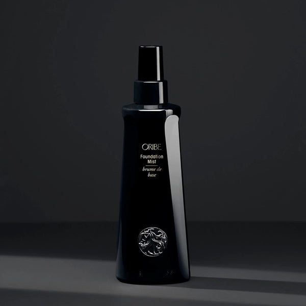 Oribe Foundation Mist – sleek black mist spray bottle for hair priming, conditioning and heat protection, with gold logo detailing.