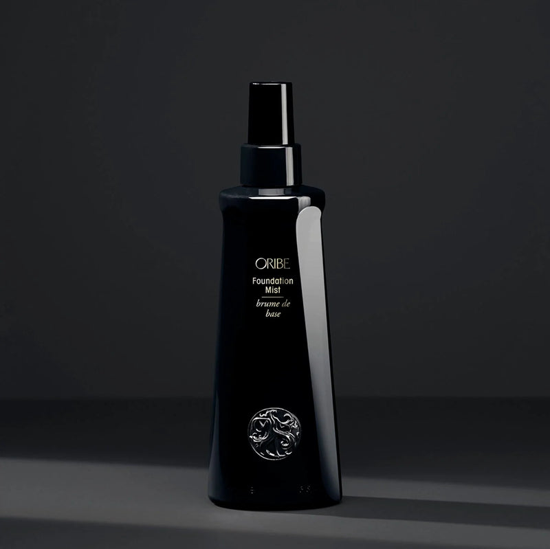 Oribe Foundation Mist – sleek black mist spray bottle for hair priming, conditioning and heat protection, with gold logo detailing.