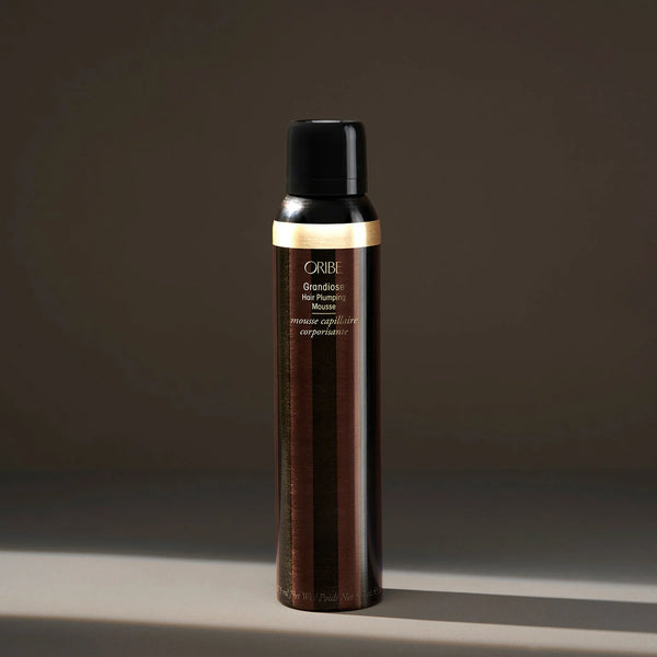 Oribe Grandiose Hair Plumping Mousse in signature gold aerosol can — a weightless, body-building mousse that adds volume, density, and soft hold to fine or limp hair.