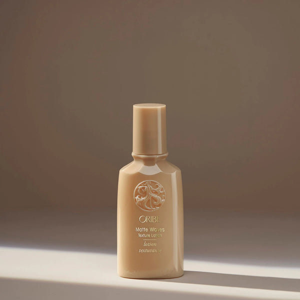 Oribe Matte Waves Texture Lotion in seafoam green tube with gold accents — a lightweight lotion that creates beachy, tousled waves with a soft, matte finish and touchable hold.