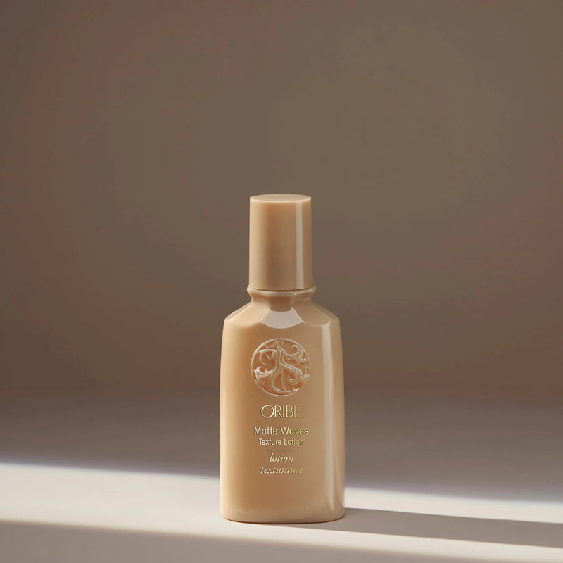 Oribe Matte Waves Texture Lotion in seafoam green tube with gold accents — a lightweight lotion that creates beachy, tousled waves with a soft, matte finish and touchable hold.