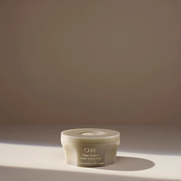 Oribe Fiber Groom Elastic Texture Paste – creamy fiber paste that creates airy separation, bounce, and elastic medium hold with subtle shine.