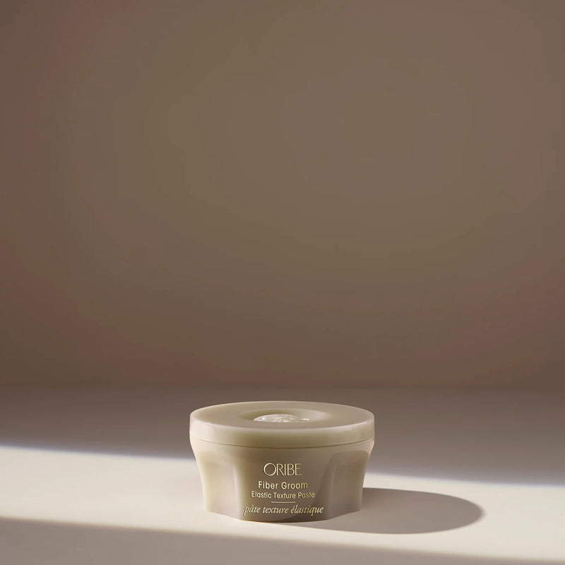 Oribe Fiber Groom Elastic Texture Paste – creamy fiber paste that creates airy separation, bounce, and elastic medium hold with subtle shine.
