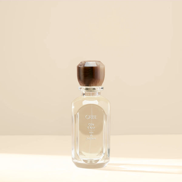 Oribe Côte d’Azur Eau de Parfum – clear luxury glass perfume bottle with rich brown faceted cap, featuring Oribe’s signature scent inspired by the French Riviera.