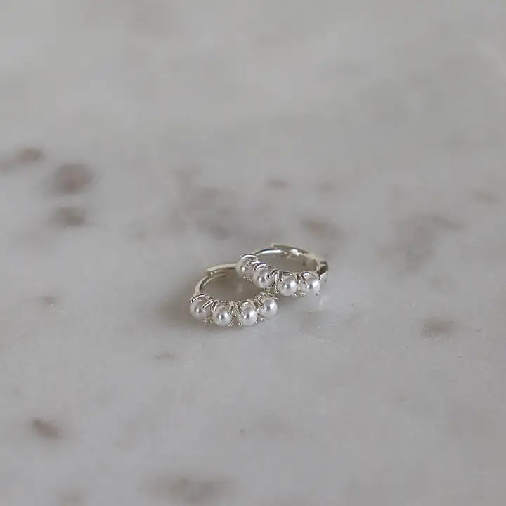 Katie Waltman Mini Pearl Hoops in silver – petite silver-plated huggie hoops adorned with a single synthetic pearl beaded along the hoop, classic and elegant.