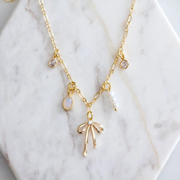 Mesa Blue charm necklace featuring CZ crystal, opalite, pearl, and a dainty bow pendant. This is an elegant layered jewelry for everyday or special occasions.
