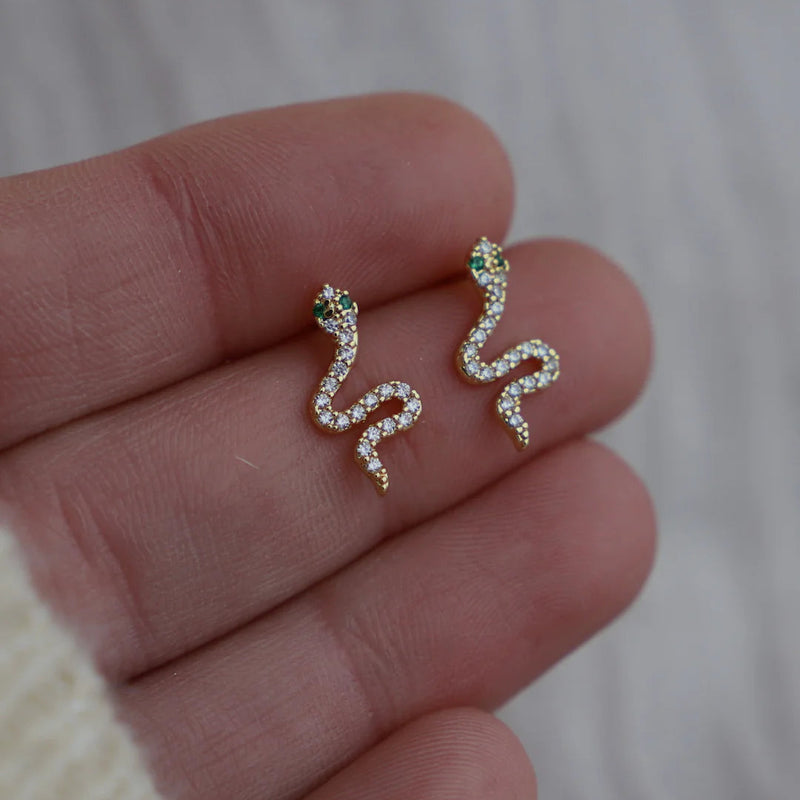 New in from Katie Waltman these CZ Emerald Snake Studs are a Stunning snake-shaped earrings featuring vibrant emerald-colored cubic zirconia for a bold, eye-catching look. Perfect for adding a touch of glamour to any outfit, these trendy earrings are a must-have for fashion-forward jewelry lovers.