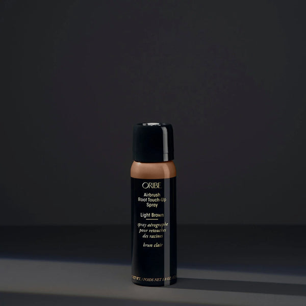 Oribe Airbrush Root Touch‑Up Spray in Light Brown – slim black aerosol can with brown sprayed top, sleek gold logo, and quick-drying microfine pigment formula for root coverage.